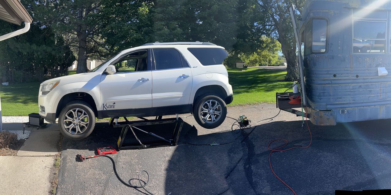 A GMC Acadia raised on a portable lift in a Pocatello driveway during a Wolf Pack Repair mobile call-out